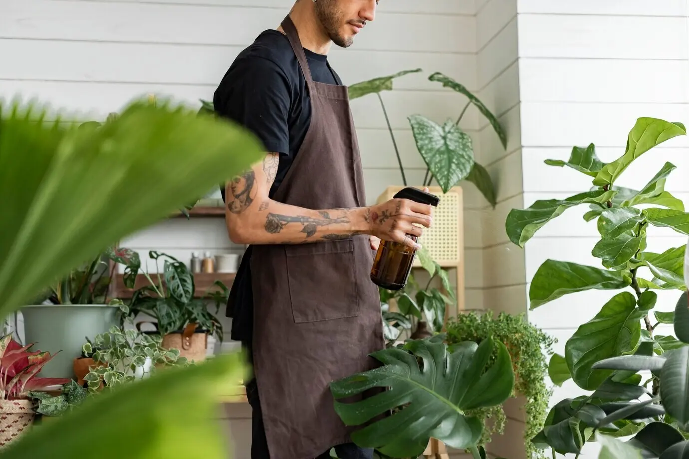 A small-business employee misting plants with a water spray