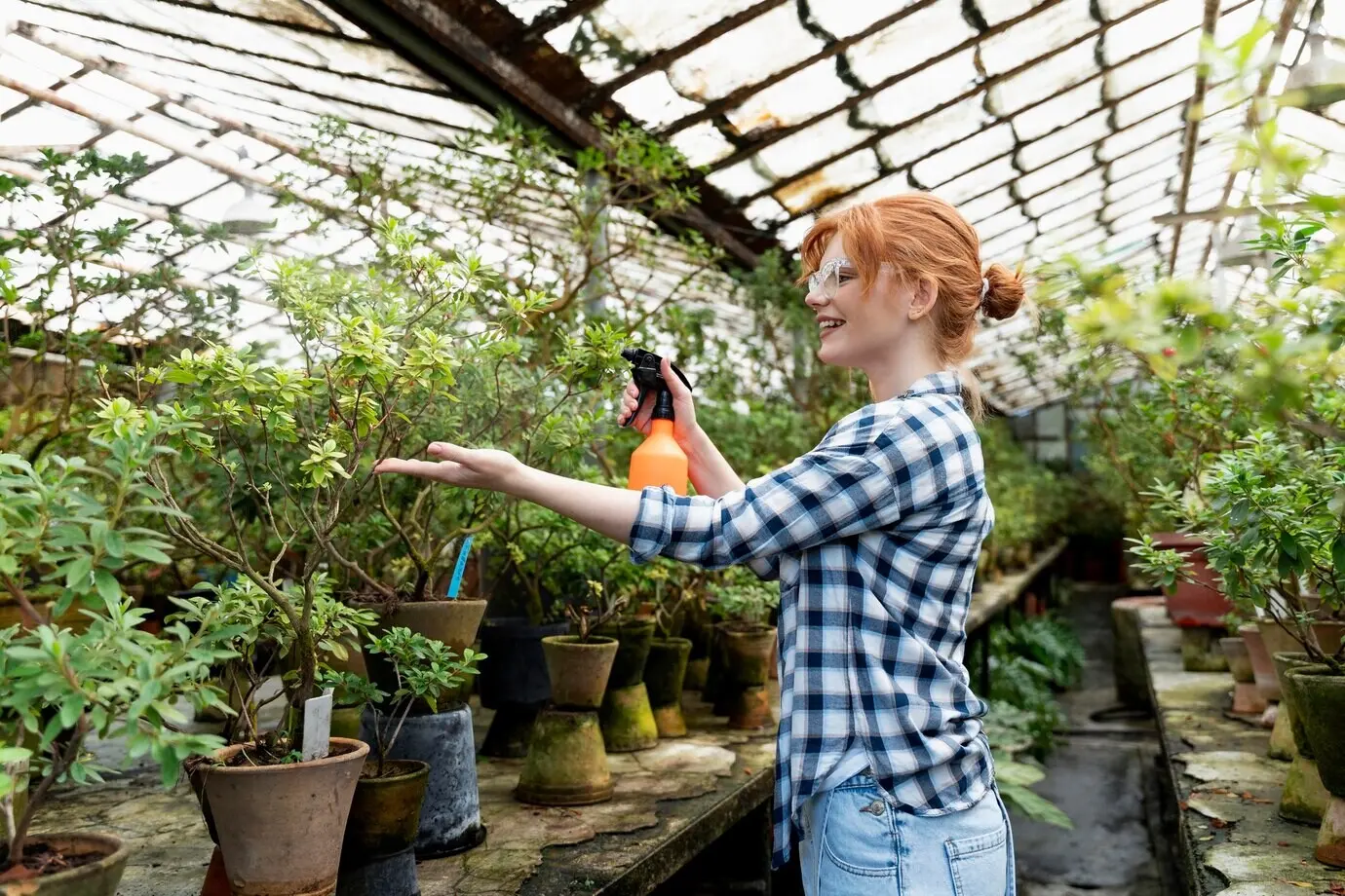 A red-haired woman tending her plants in a greenhouse.